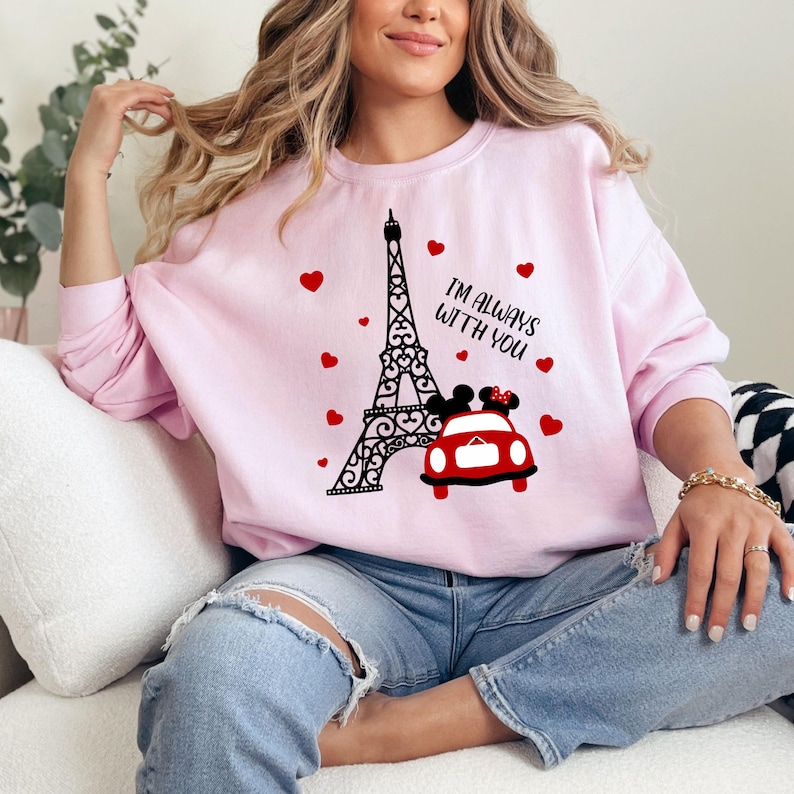 May include: A pink sweatshirt with a black and white Eiffel Tower graphic, a red car with Mickey Mouse and Minnie Mouse inside, and the text "I'm always with you".