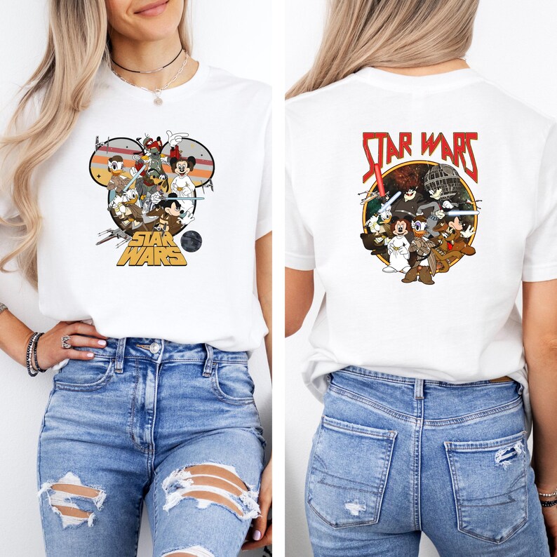 May include: White t-shirt featuring a colorful graphic of Disney characters in a Star Wars theme. The front design includes Mickey Mouse, Donald Duck, and other characters. The back of the shirt also has a Star Wars graphic. The shirt is paired with blue jeans.