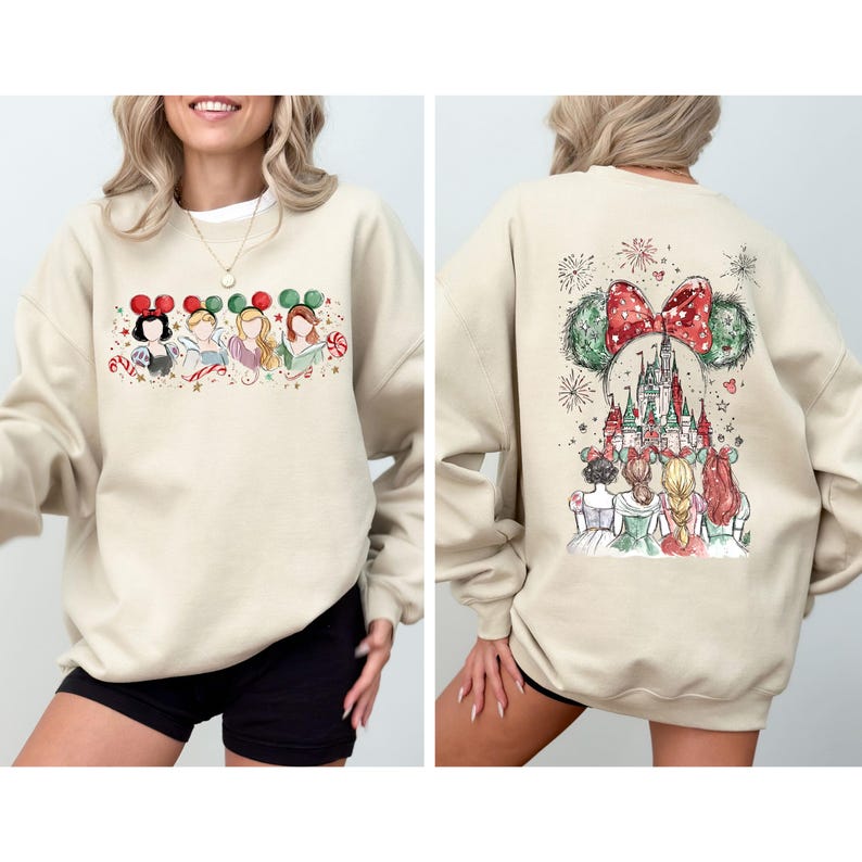 May include: Beige sweatshirt featuring a festive design. The front showcases cartoon characters with holiday-themed mouse ears and candy canes. The back displays a castle, fireworks, and characters with mouse ears, all in a watercolor style.