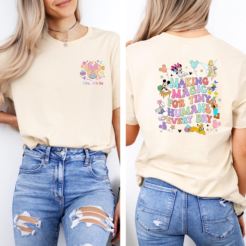 May include: Cream-colored t-shirt with a colorful graphic on the front and back. The front features a Minnie Mouse design with the text "Mrs. White." The back displays the phrase "Making Magic for Tiny Humans Every Day" with cartoon characters.