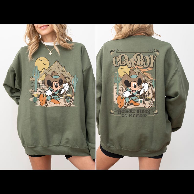 May include: Green sweatshirt with a cartoon image of Mickey Mouse dressed as a cowboy with the text "COWBOY" and "DESERT VIBES ON MY MIND" printed on the back.