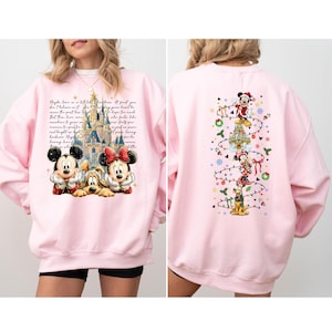 Puede incluir: Sudadera rosa con un dise&ntilde;o navide&ntilde;o con Mickey y Minnie Mouse y Pluto. La parte delantera tiene un gr&aacute;fico de castillo y texto. La parte trasera tiene un dise&ntilde;o de &aacute;rbol de Navidad con Mickey, Minnie y Pluto.