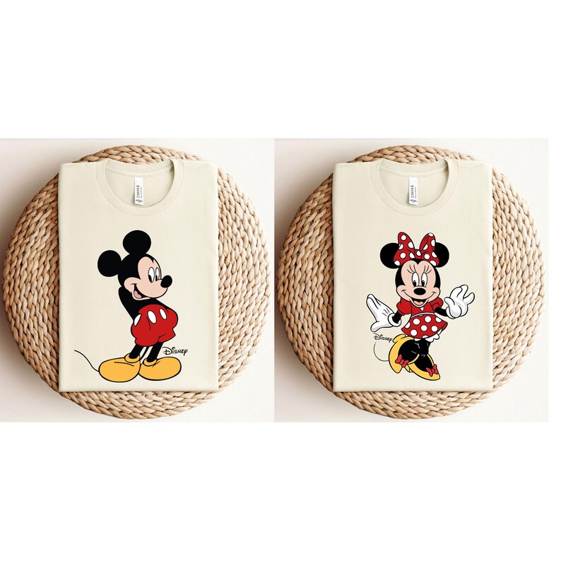 K&ouml;nnte beinhalten: Zwei cremefarbene T-Shirts mit einem Mickey Mouse und Minnie Mouse Grafikdruck. Das Mickey Mouse Shirt hat den Text "Disney" aufgedruckt.