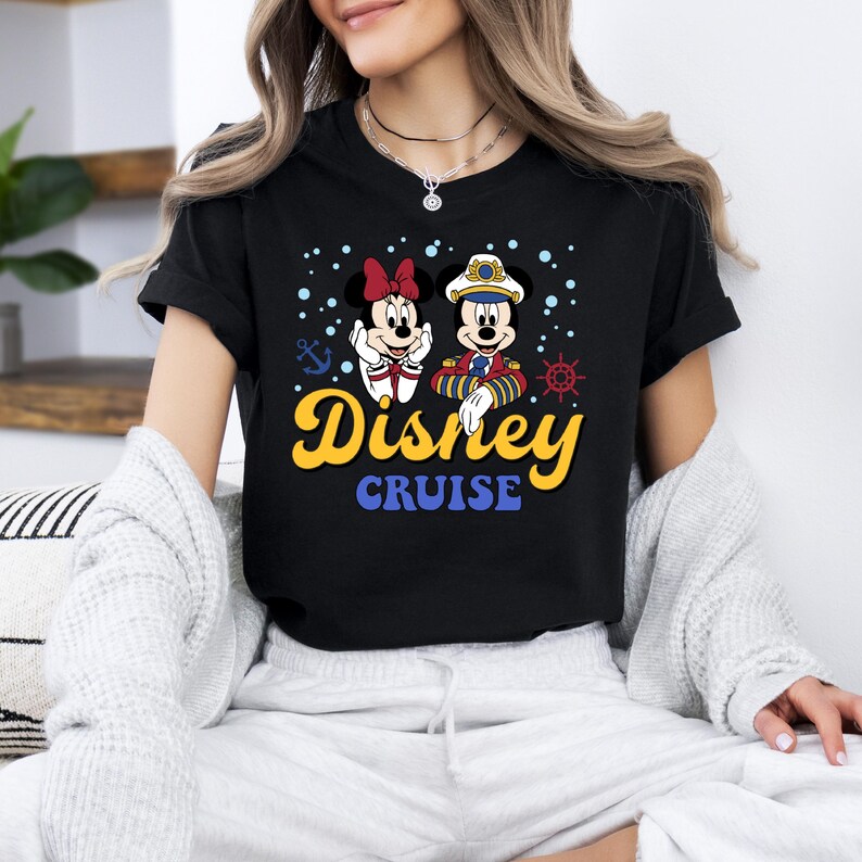 May include: Black t-shirt with a graphic of Mickey Mouse and Minnie Mouse dressed as a captain and a sailor. The text "Disney Cruise" is printed below the characters.