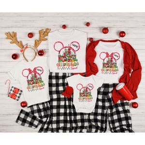 Puede incluir: Un conjunto de camisetas y pijamas blancos de Christmas Squad con un dise&ntilde;o de Mickey Mouse. Las camisetas tienen un gr&aacute;fico de castillo rojo y verde con el texto "Christmas Squad". Tambi&eacute;n se incluye una camisa roja de manga larga y un body para beb&eacute;.