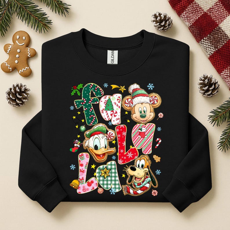 K&ouml;nnte beinhalten: Schwarzes Sweatshirt mit einem farbenfrohen "Fa La La"-Design mit Mickey Mouse, Donald Duck und Pluto in festlicher Weihnachtskleidung. Das Design umfasst Zuckerstangen, Schneeflocken und andere weihnachtliche Elemente.
