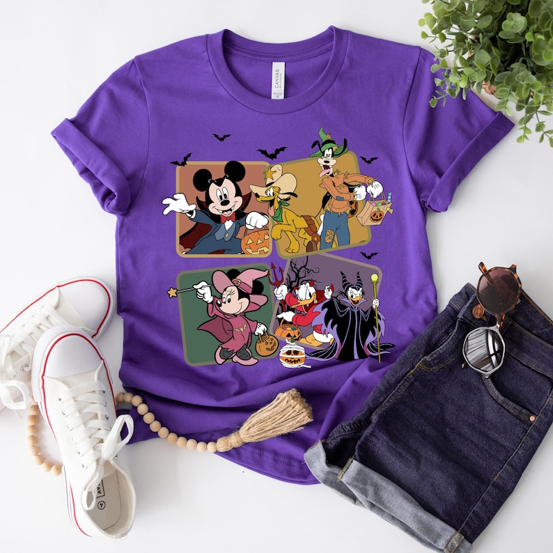 K&ouml;nnte beinhalten: Lilafarbenes T-Shirt mit einem Motiv von Mickey Mouse, Goofy, Donald Duck und Maleficent, die sich f&uuml;r Halloween verkleidet haben. Die Figuren halten K&uuml;rbisse und S&uuml;&szlig;igkeiten.