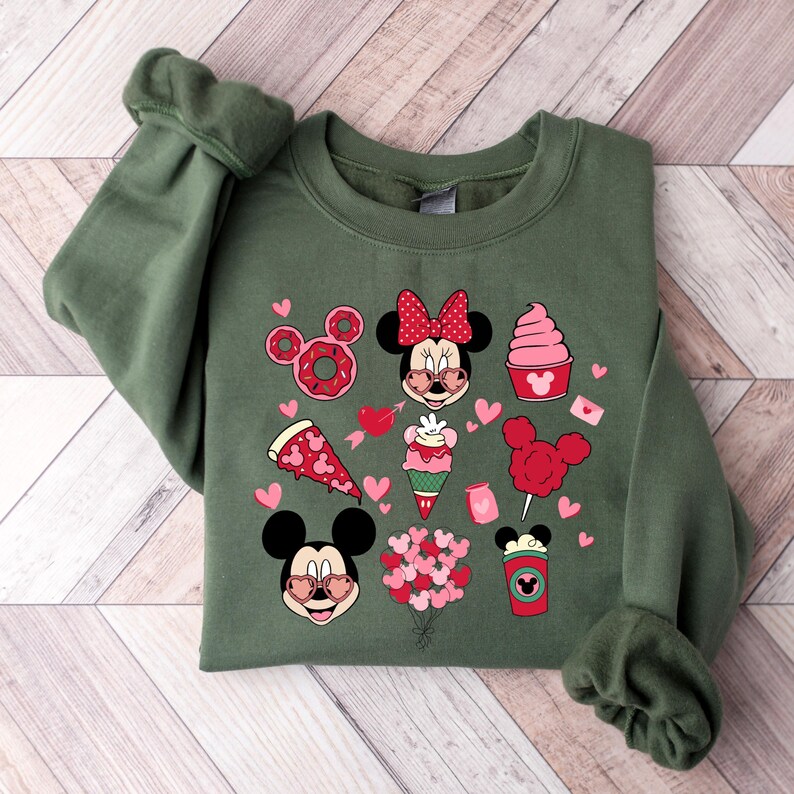 May include: A green sweatshirt with a Valentine's Day theme featuring Mickey and Minnie Mouse. The design includes hearts, donuts, pizza, ice cream, cotton candy, and a coffee cup.