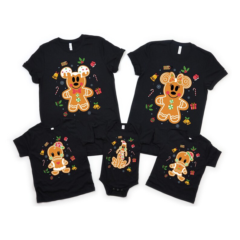 May include: A set of five black t-shirts featuring gingerbread characters. The shirts have a Christmas theme with red and green accents. The characters include Mickey Mouse, Minnie Mouse, Pluto, and a gingerbread person.