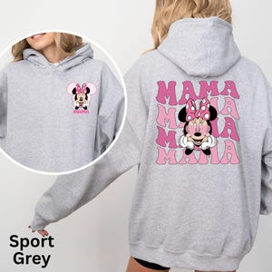 Puede incluir: Sudadera gris deportiva con un gr&aacute;fico de Minnie Mouse y la palabra "MAMA" en rosa. La parte delantera de la sudadera tiene un gr&aacute;fico m&aacute;s peque&ntilde;o de Minnie Mouse. La parte trasera tiene un gr&aacute;fico m&aacute;s grande de Minnie Mouse con la palabra "MAMA" repetida.