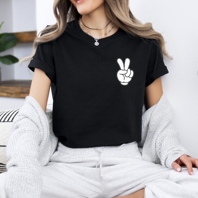 May include: Black t-shirt with a white peace sign graphic on the left chest.