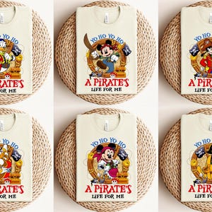 K&ouml;nnte beinhalten: Sechs beigefarbene T-Shirts mit jeweils einem Cartoon-Piratencharakter. Die Charaktere sind Mickey Mouse, Donald Duck, Goofy, Pluto und ein gelber Hund. Jedes Shirt tr&auml;gt den Text "Yo Ho Yo Ho A Pirate's Life For Me".