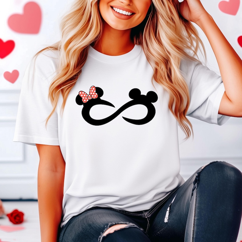 May include: White t-shirt featuring a black infinity symbol design. One side of the infinity symbol has a red bow and black ears, while the other side has black ears.