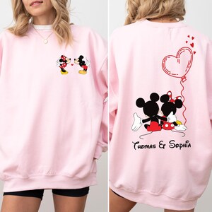 May include: Pink sweatshirt with a graphic of Mickey and Minnie Mouse kissing on the front and a heart with the text "Thomas & Sophia" on the back.