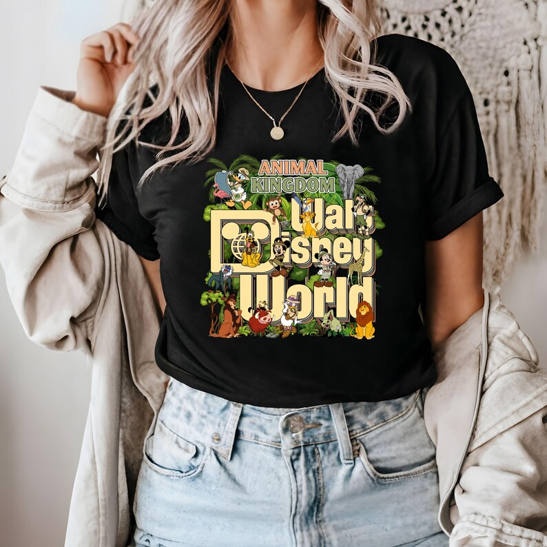 Pu&ograve; includere: Maglietta nera con una stampa grafica di vari personaggi Disney di Animal Kingdom, tra cui Topolino, Paperino, Pippo e Simba. Il testo "Animal Kingdom" e "Walt Disney World" &egrave; stampato sulla maglietta.