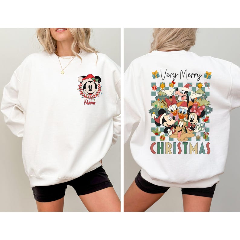 May include: White sweatshirt featuring Mickey Mouse in a Santa hat and a Christmas wreath on the front. The back of the sweatshirt has a graphic of Disney characters with the words "Very Merry Christmas".