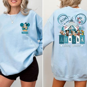 May include: Light blue sweatshirt with a Mickey Mouse graphic and the text "Alaska Disney Wonder" on the front. The sweatshirt has a crew neck and long sleeves.