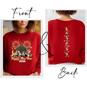 May include: Red sweatshirt with a front graphic featuring a black and gold sphere, fireworks, and Disney characters. The text "Happy New Year 2026" is below. The back of the sweatshirt has a vertical line of Disney characters.
