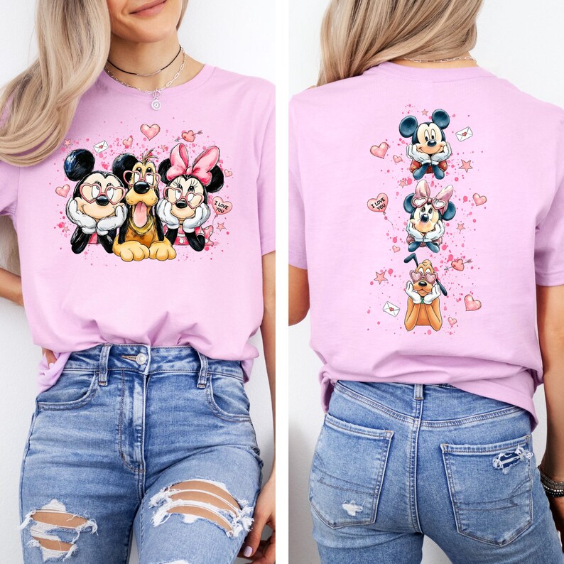May include: A light pink t-shirt featuring a graphic of Mickey Mouse, Minnie Mouse, and Pluto with hearts and the text "I Love". The back of the shirt shows the same characters in a vertical design. The shirt is made of a soft material.