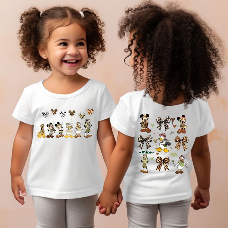 May include: Two children wearing white t-shirts with Disney character designs. The front of one shirt features Mickey Mouse, Minnie Mouse, Donald Duck, and Goofy holding balloons. The back of the other shirt features Mickey Mouse, Minnie Mouse, Donald Duck, and Goofy wearing safari hats and holding bows.
