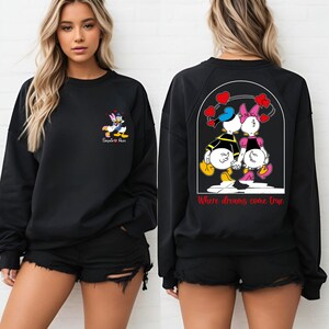 May include: Black sweatshirt with a graphic of Donald Duck and Daisy Duck holding hands. The text "Where dreams come true" is printed on the back of the sweatshirt.