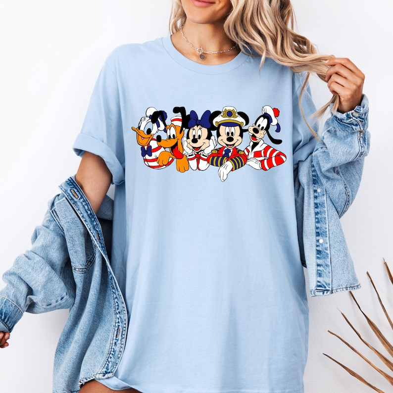 Peut inclure: T-shirt bleu clair avec un motif de Mickey Mouse, Minnie Mouse, Donald Duck, Dingo et Pluto habill&eacute;s en marins.