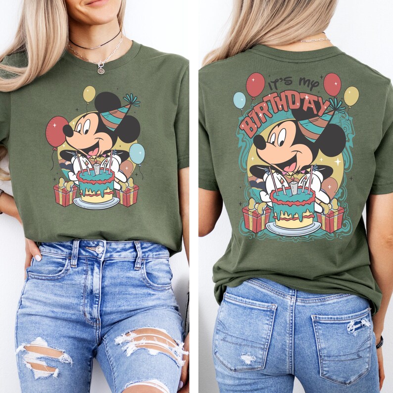 以下が含まれることがあります： 緑色のTシャツに、パーティーハットをかぶり、誕生日ケーキを持ったミッキーマウスのヴィンテージスタイルのイラストが描かれています。Tシャツの後ろには「It's my Birthday」という文字がプリントされています。