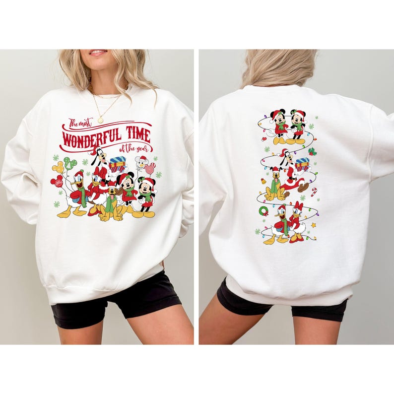 May include: White sweatshirt featuring a festive design with Disney characters. The front displays Mickey, Minnie, Donald, and Goofy with the text "The Most Wonderful Time of the Year." The back shows the characters in a vertical Christmas lights design.