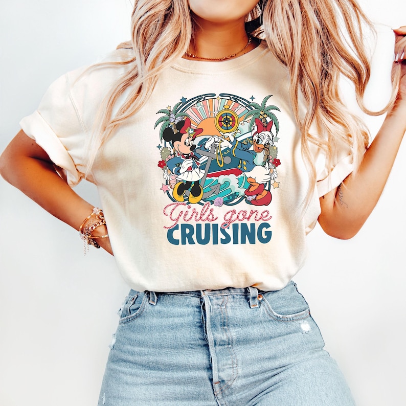 May include: A white t-shirt with a colorful graphic of Mickey Mouse and Donald Duck dressed as sailors on a ship. The text "Girls gone CRUISING" is printed below the graphic.
