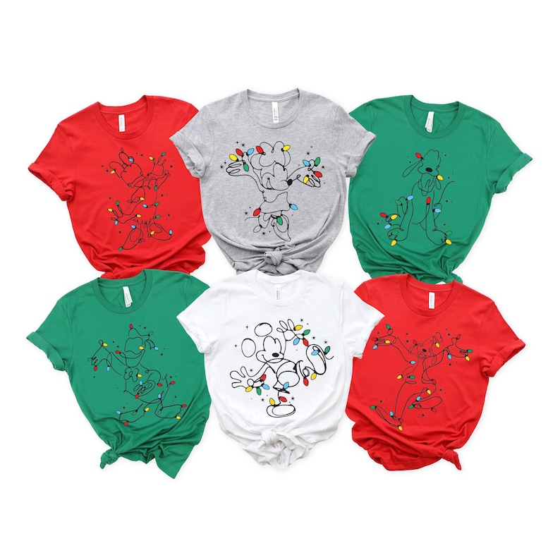 May include: A collection of six short-sleeved t-shirts in various colors: red, gray, green, and white. Each shirt features a cartoon character design wrapped in Christmas lights. The shirts are suitable for the holiday season.