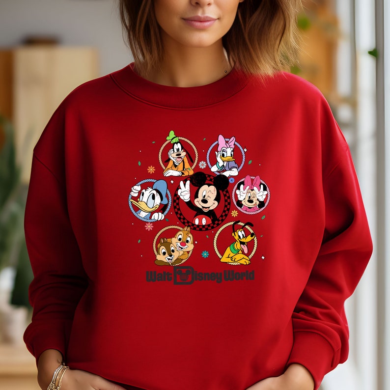 Op de afbeelding: Rood sweatshirt met een afbeelding van Mickey Mouse en zijn vrienden in een cirkel rond het Walt Disney World logo.