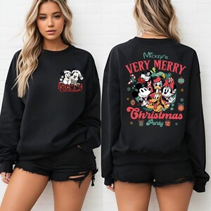 Puede incluir: Sudadera negra con un dise&ntilde;o navide&ntilde;o de Mickey Mouse en la parte delantera y un dise&ntilde;o de fiesta navide&ntilde;a de Mickey Mouse en la parte trasera.