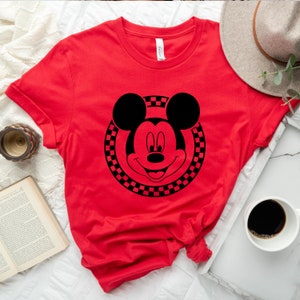 May include: Red t-shirt with a black and white chequered circle around a black Mickey Mouse head.