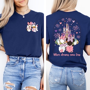 Pu&ograve; includere: Una maglietta blu navy con una grafica di Topolino e Minnie Mouse davanti al Castello di Cenerentola. La parte posteriore della maglietta ha una grafica pi&ugrave; grande del castello con fuochi d'artificio e il testo "Where dreams come true".