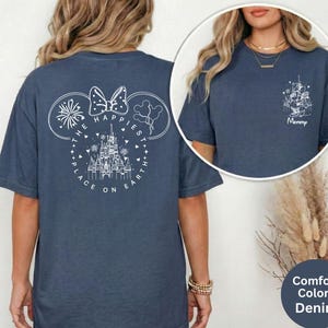 May include: Denim blue t-shirt with a white graphic of Mickey Mouse ears, fireworks, a castle, and the text "The Happiest Place on Earth." A smaller graphic on the front says "Mommy."