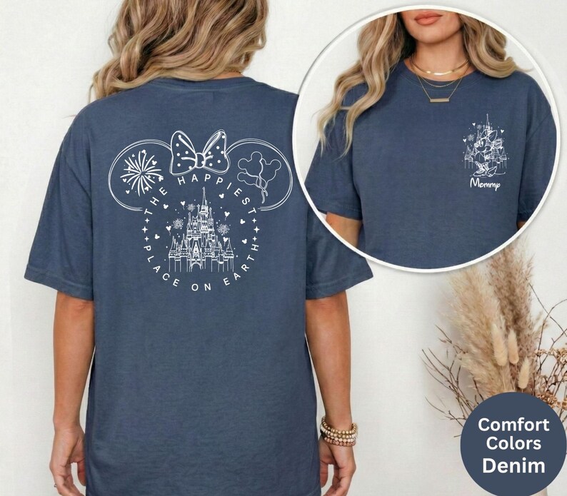 May include: Denim blue t-shirt with a white graphic of Mickey Mouse ears, fireworks, a castle, and the text "The Happiest Place on Earth." A smaller graphic on the front says "Mommy."