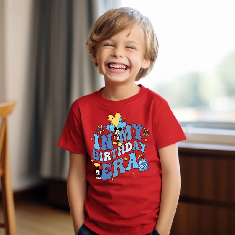 May include: A red short-sleeved t-shirt with a graphic of Mickey Mouse and the text "In My Birthday Era".
