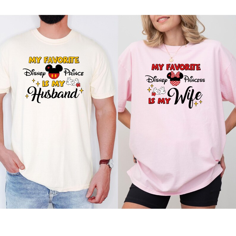 May include: Two t-shirts, one cream and one pink, with Disney-themed graphics. The cream shirt says "My Favorite Disney Prince is My Husband" with Mickey Mouse imagery. The pink shirt says "My Favorite Disney Princess is My Wife" with Minnie Mouse imagery.