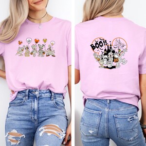 K&ouml;nnte beinhalten: Hellrosa T-Shirt mit Halloween-Motiven. Auf der Vorderseite sind Cartoon-Figuren als Mumien mit Luftballons abgebildet. Auf der R&uuml;ckseite befinden sich ein Schloss, Spinnweben und der Schriftzug "BOO!!" in Schwarz.