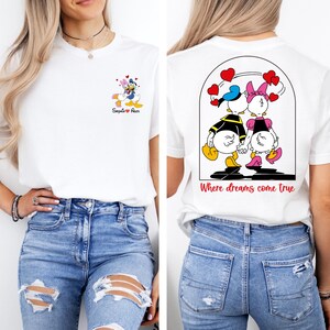 May include: White t-shirt with a cartoon image of Donald Duck and Daisy Duck holding hands. The back of the shirt has a larger image of the couple with the text "Where dreams come true".