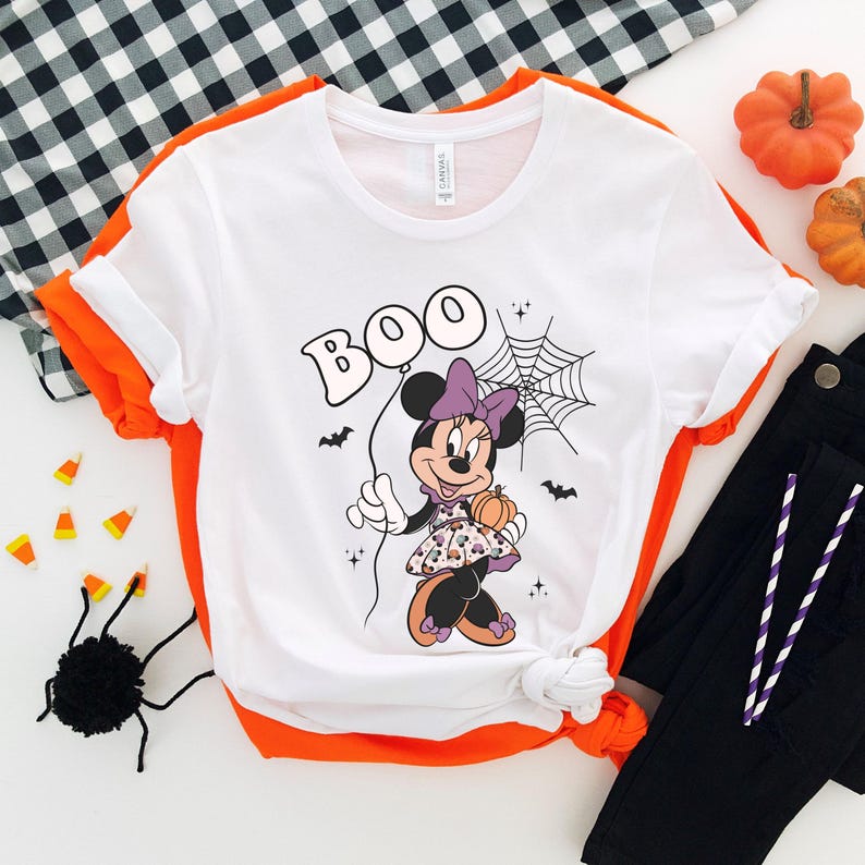 May include: White t-shirt with a cartoon image of Minnie Mouse holding a pumpkin and a balloon that says "BOO".