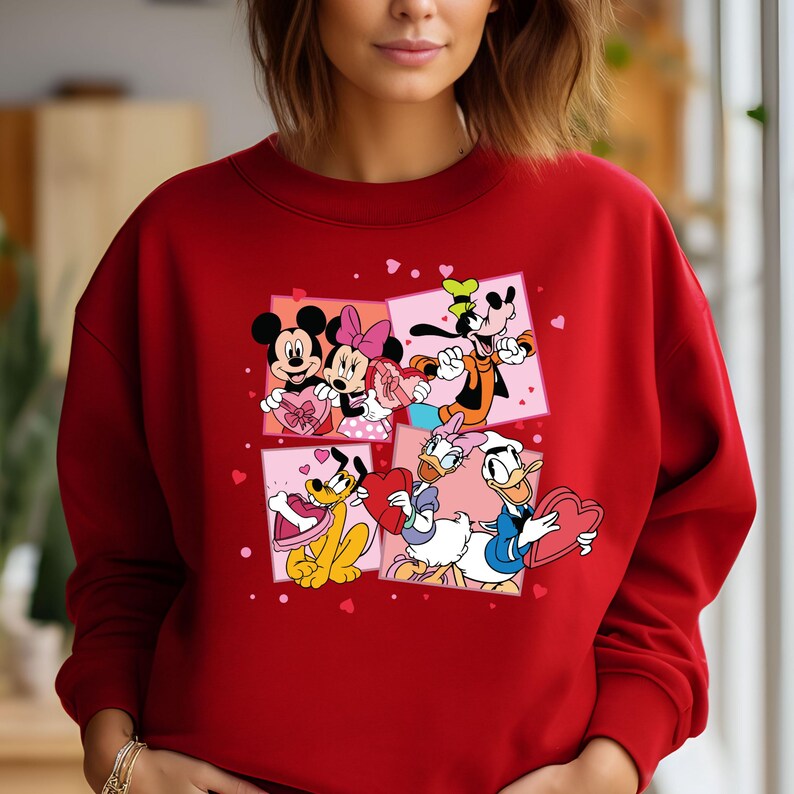May include: Red sweatshirt with a Valentine's Day design featuring Mickey Mouse, Minnie Mouse, Donald Duck, Goofy, and Pluto. The characters are holding hearts and surrounded by pink hearts.