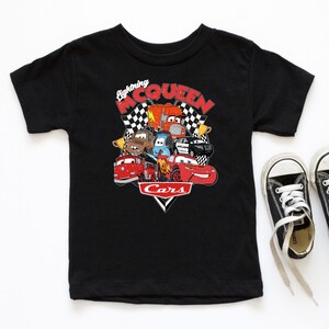 May include: Black t-shirt with a graphic of Lightning McQueen and other Cars characters. The graphic features a checkered flag background and the text "Lightning McQueen" and "Cars".