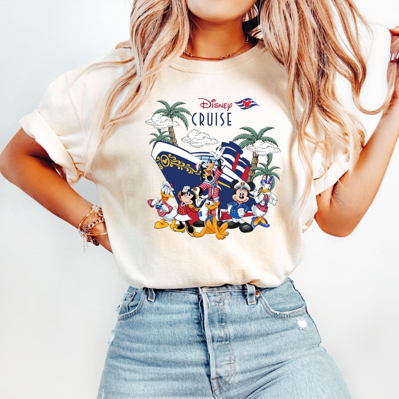 Pu&ograve; includere: Una maglietta bianca con una grafica di Topolino e i suoi amici su una nave da crociera Disney. Il testo "Disney Cruise" &egrave; stampato sulla maglietta.