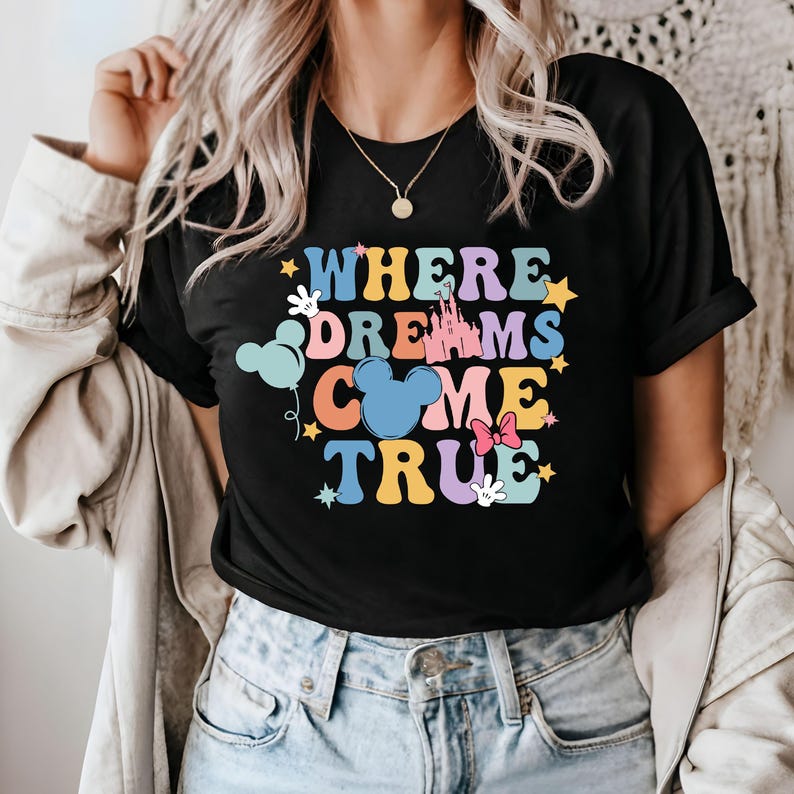 May include: Black t-shirt with a colorful graphic that says "Where Dreams Come True" with a castle, Mickey Mouse ears, stars, and balloons.
