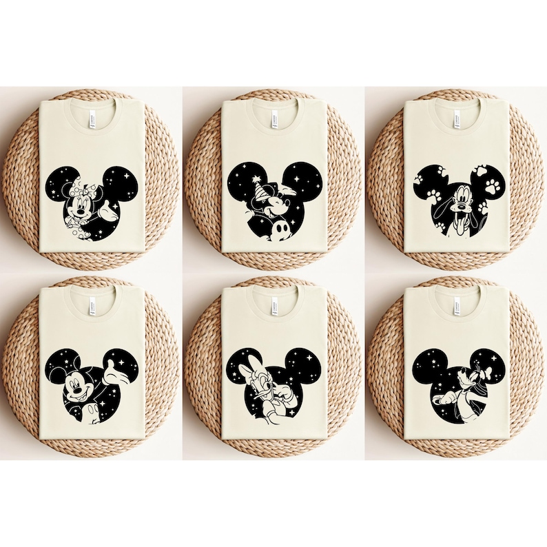 May include: Six cream-coloured t-shirts featuring black Mickey Mouse head silhouettes with different character designs. Each design includes characters like Minnie Mouse, Goofy, and Donald Duck, set against a starry background.