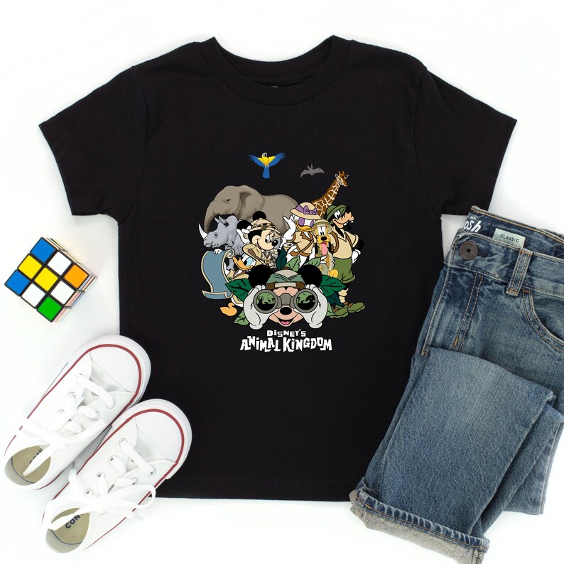 Może przedstawiać: Czarny T-shirt z grafiką przedstawiającą Myszke Miki i jej przyjaci&oacute;ł przed dżunglą. Pod obrazkiem znajduje się napis "Disney's Animal Kingdom".