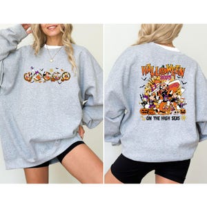 May include: A heather gray sweatshirt with a Halloween-themed graphic on the front and back. The front features cartoon characters in a circular design, while the back displays the text "Halloween 2025" and "On The High Seas" with pumpkins and other Halloween elements.