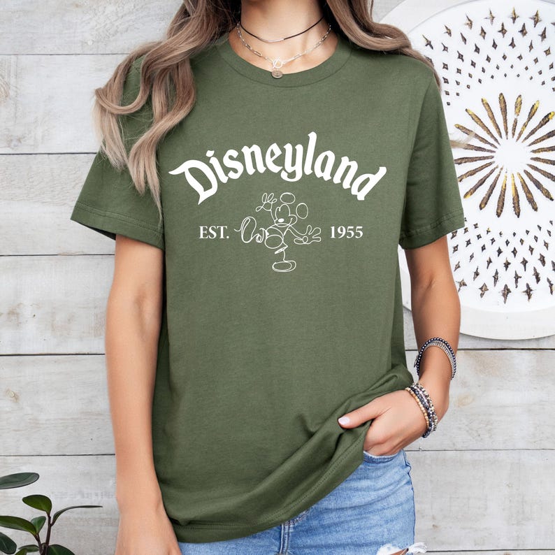 May include: A green t-shirt with a white graphic of Mickey Mouse and the text "Disneyland Est. 1955".