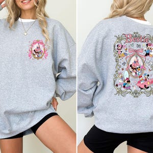 May include: Gray sweatshirt with a pink and white graphic of Disney characters in a frame. The text "Bestie" is on the graphic.
